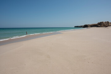 Fototapeta na wymiar Woman alone at a wild Beach of Ras Al Jinz and going to swim in the ocean, Sultanate of Oman. 