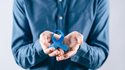 men hands holding Blue ribbon for supporting people living and illness, Colon cancer, Colorectal cancer, Child Abuse awareness, world diabetes day, International Men's Day