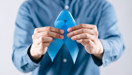 men hands holding Blue ribbon for supporting people living and illness, Colon cancer, Colorectal cancer, Child Abuse awareness, world diabetes day, International Men's Day