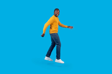 Fototapeta na wymiar Emotional african american mature man jumping up on blue