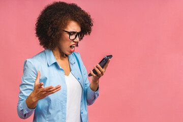 Angry mixed race caucasian - african american woman shouting in mobile phone, isolated over pink...