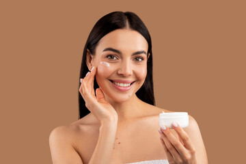 Beautiful woman applying facial cream on her skin