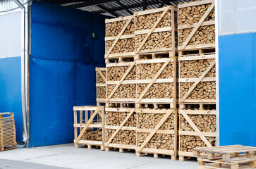 Chopped dry firewood stacked in large wooden containers. Dry chopped firewood in the dryer. Storage of dry chopped firewood. Ready firewood for sale in the warehouse.