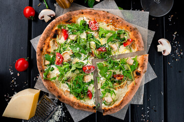 Pizza with cheese parmesan, chicken, arugula, cherry tomatoes and spices.
