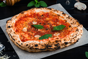 Red pizza with tomato sauce, garlic, spinach on thick dough.