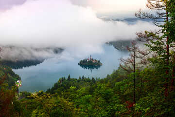 Aerial view of Island in Bled Lake, with Bled city in background. Church and other buildings in the...