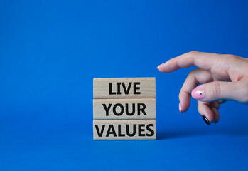 Live your values symbol. Concept words Live your values on wooden blocks. Beautiful blue background. Businessman hand. Business and Live your values concept. Copy space.