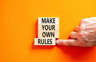 Make your own rules symbol. Concept words Make your own rules on wooden cubes. Beautiful orange table orange background. Businessman hand. Business motivational make your own rules concept. Copy space