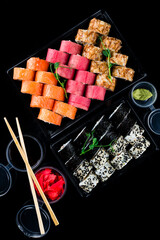 Sets of maki sushi rolls with tuna, salmon, cream cheese, rice paper, shrimp, sweet pepper, wasabi, ginger, soy sauce in box.