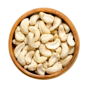 Cashew nuts, raw cashews in a wooden bowl. Seeds of shelled cashew tree fruits, Anacardium occidentale. Snack nuts, can be eaten on its own, used in recipes or processed into cashew butter or cheese.