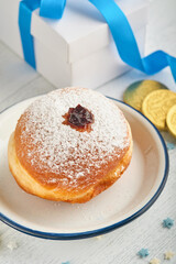 Happy Hanukkah. Hanukkah sweet doughnuts, gift boxes, white candles and chocolate coins on white wooden background. Image and concept of jewish holiday Hanukkah. Top view.