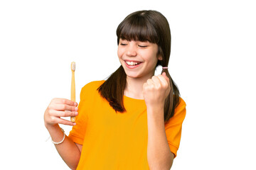 Little caucasian girl brushing teeth over isolated background celebrating a victory