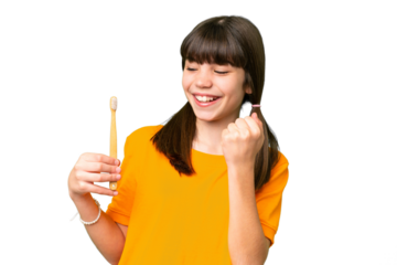 Little caucasian girl brushing teeth over isolated background celebrating a victory