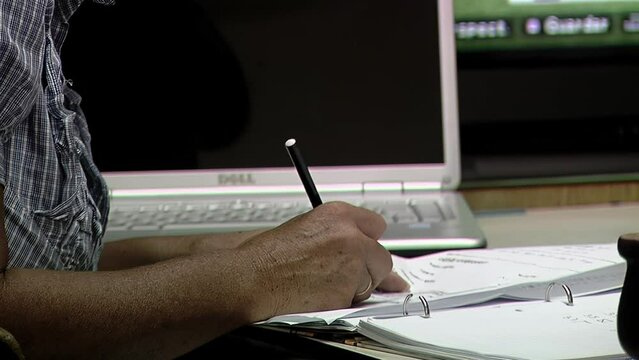 Man Holding Black Pen Writing on Paper at his Office. Close Up. 