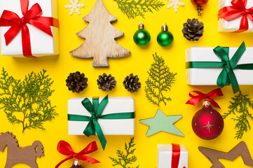 Flat lay with christmas gift boxes, toys, juniper and cones on color background