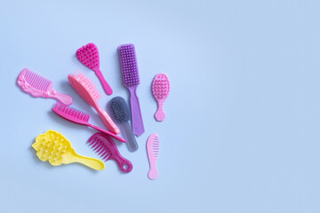 Hair care is a creative concept. Colored doll combs on a blue background. Copy space