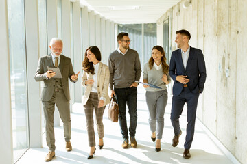 Group of corporate business professionals walking through office corridor