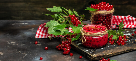 Preserved berry Homemade jam. Glass jar with red currant jam on a dark background. Long banner format. top view