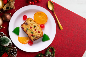 Cake with colored candied fruit on a table with Christmas decorations. Christmas Dessert.