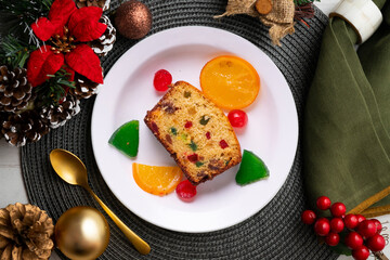 Cake with colored candied fruit on a table with Christmas decorations. Christmas Dessert.