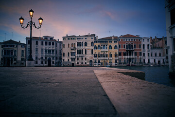 Venice evening dusk landscape with the view of venetian houses on the Grand canal and the square with victorian vintage antique street warm yellow lights lantern in the foreground