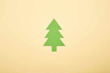 Obraz premium Green Сhristmas tree shape paper applique isolated on the bright solid fond plain yellow background. Postcard template
