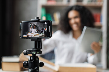 Focus on smart phone screen , woman recording video on phone camera while unpacking box with new wireless tablet. Female influencer sharing with subscribers her positive feedback about new order.