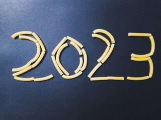 Année 2023 en pâtes macaronis sur papier noir, crise