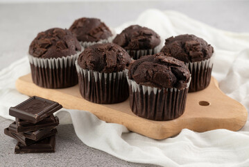 Chocolate muffins on a wooden plank on a gray table. The concept of home baking, recipe.
