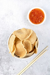 Kerupuk udang - traditional indonesian shrimp crackers on a gray background with sweet chili sauce. Shrimp chips. Thai snacks. Top view.