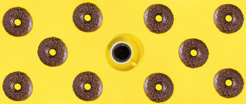 Donut with chocolate glaze and coffee cup on the yellow background. Banner. Flat lay. Pattern.