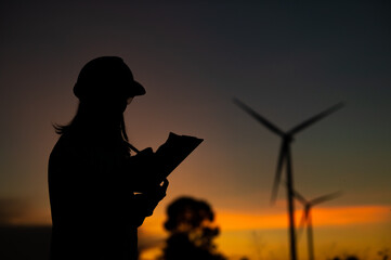 Asian Man engineers working and holding the report at wind turbine farm Power Generator Station on mountain,Thailand people,Technician man at site of work