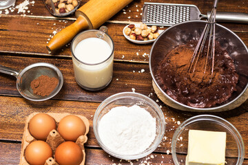 Ingredients for cooking chocolate pastry from above on wooden background