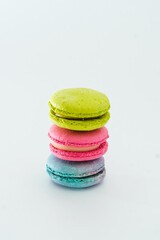 Brightly colored stacked up French macarons. Tasty colourful macaroons. Blue, pink and green macaroons isolated on white background. French pastry made from egg whites. Concept of food, desserts