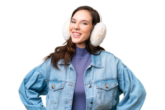 Young caucasian woman wearing winter muffs over isolated background posing with arms at hip and smiling