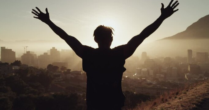 Running, success and fitness man celebrate goal, achievement and freedom on a mountain road with hands raised with silhouette and city view. Athlete outdoor for exercise, workout and cardio at sunset