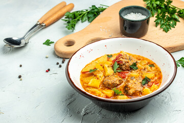 stew vegetables with meatball, potato, onion, zucchini with tomato sauce, garlic and herbs in a white bowl, place for text, top view