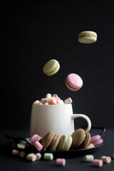 A cup of hot coffee with milk and delicious pasta cakes, small marshmallows.