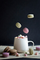 A cup of hot coffee with milk and delicious pasta cakes, small marshmallows.