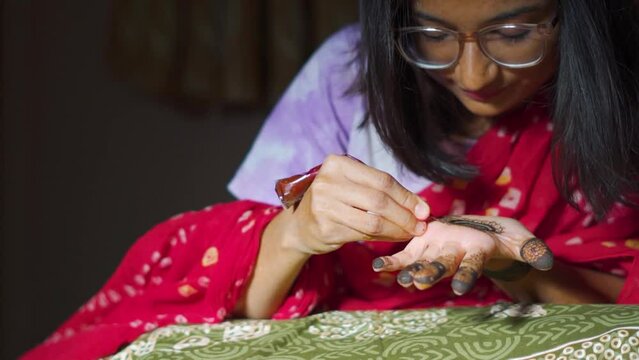 Portrait of Indian girl applying traditional Mehndi on her palm. Wedding season in India. Mehendi art or Heena Tattoo on the hand of beautiful girl in Bhuj, Kutch, India.