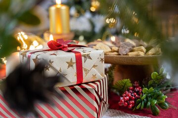Red and white Christmas gifts tied with a ribbon under the Christmas tree along with Christmas decorations and food