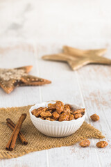 Fototapeta na wymiar Bowl of sweet candied almonds on white rustic wooden background