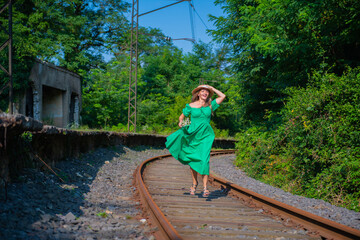 one young woman in a green dress runs along the railway