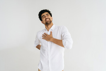 Studio portrait of frustrated bearded man in shirt touching injured sore back, suffering lower lumbar discomfort, muscle pain of overwork, pinched nerve and grimacing on white isolated background.