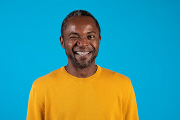 Headshot of handsome black man winking on blue