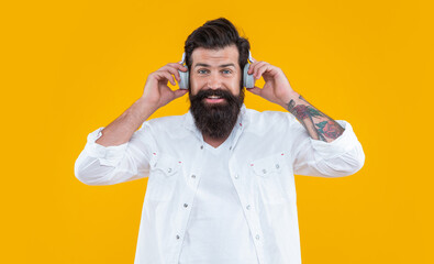 Fototapeta premium studio shot of cheerful hipster holding headphones to listen ebook. man hipster listen ebook
