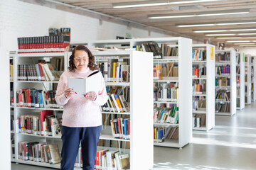 Elderly person reading a book in a public library. Space for text.