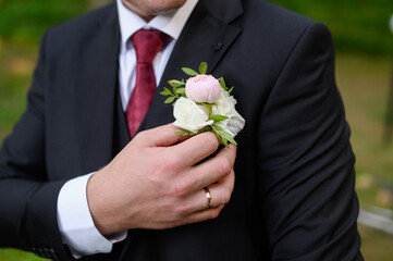  Portrait of a man adjusting his boutonniere on his jacket. No face. Men's style concept, groom's...