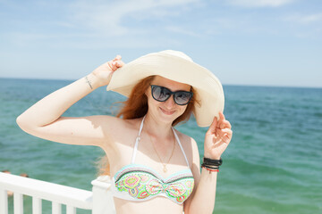 young red-haired girl in a hat on the background of the sea