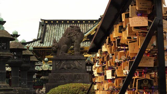 Sanctuaire japonais avec statue de lion, amulettes votives et lanternes de pierre